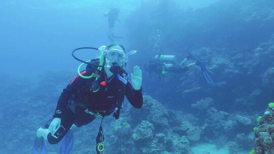 潜水员在海底向摄像机挥手