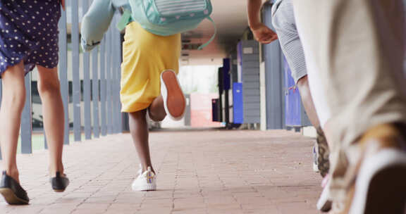 多样化的男老师和快乐的小学生在学校跑步