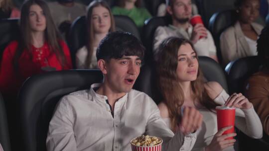 年轻夫妇在电影院看电影吃爆米花
