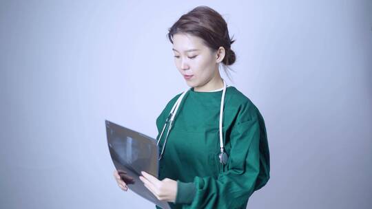 身穿手术服,手拿X光片医学影像的亚洲美女