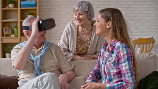 母女笑着看着戴着虚拟眼镜的父亲