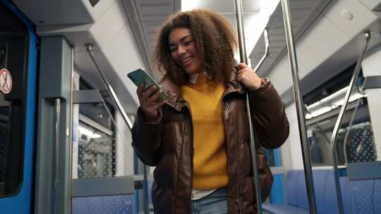 肖像开朗的非洲女性乘坐地铁并使用智能手机上网和视频素材模板下载
