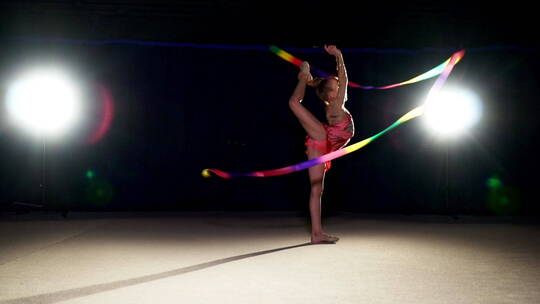 女孩跳舞与节奏体操丝带在夜间的慢动作