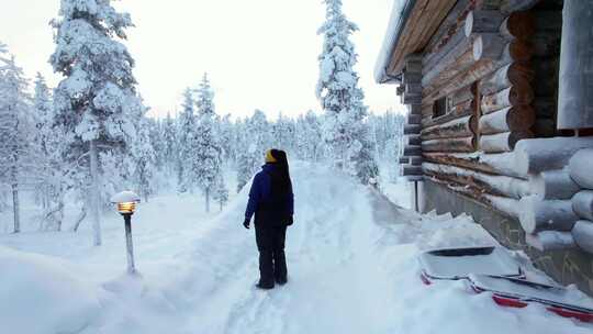 女孩眺望雪景，站在芬兰拉普兰的小屋旁，北