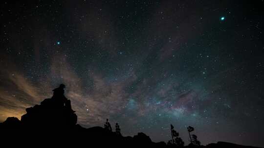 坐在星空下岩石上的人延时