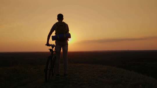 日落时山顶上的山地自行车骑手