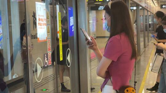 站台等待的美女看手机资讯摇地铁进站