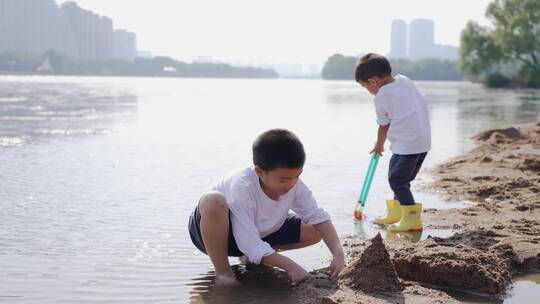小男孩在河边的沙滩上挖沙子堆城堡