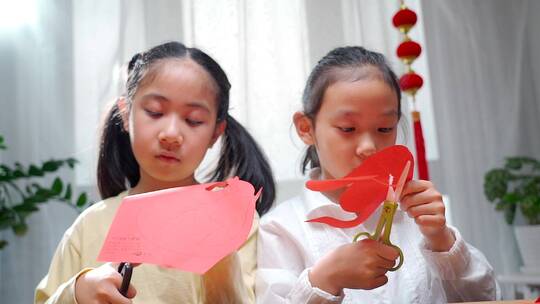 两名认真玩剪纸游戏的中国女孩