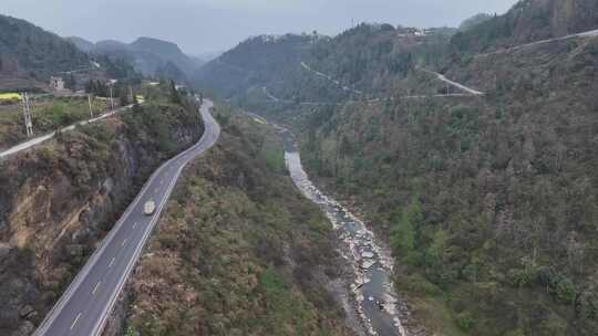 山间公路航拍，一旁有小溪相伴