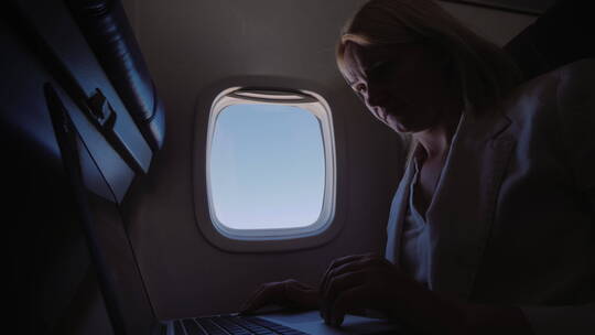 商业女人在飞行中使用笔记本电脑