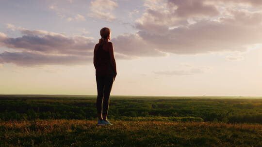 女人站在日落时分的草原上