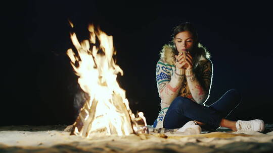 女孩坐在篝火边喝茶