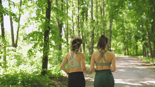 两个女运动员在树林里跑步的背视图视频素材模板下载