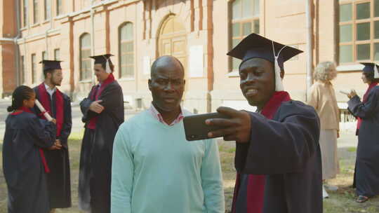毕业日期间，单身汉用智能手机和父亲自拍