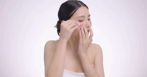 特写美容脸亚洲女性使用眼垫，眼部护理护理，皮肤清新干净。
