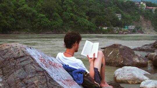 男人在河边看书