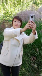 秋天在公园用手机自拍的中国女性