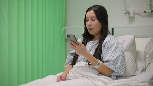 在病床上玩电话的女人视频素材模板下载