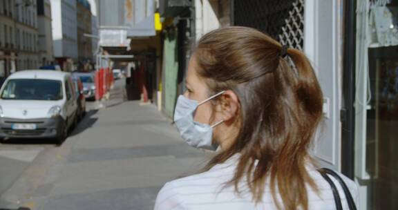 女人戴着口罩步行在城市街道