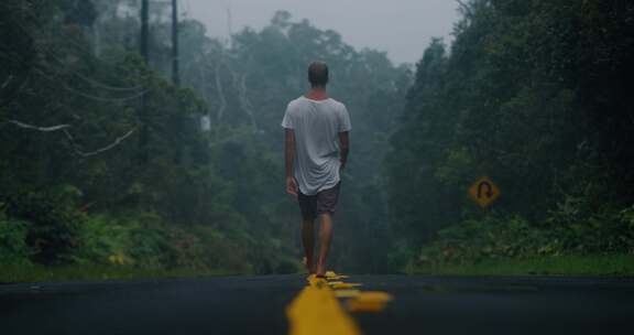 一个人在黑暗的日子里走在森林附近的路上