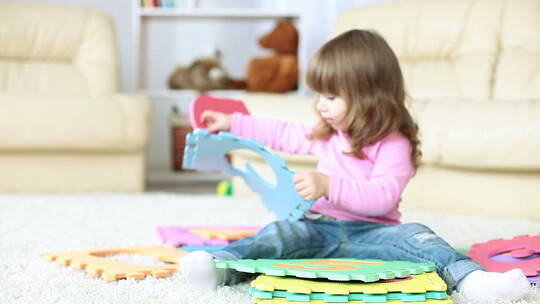 女孩坐在地毯上玩玩具
