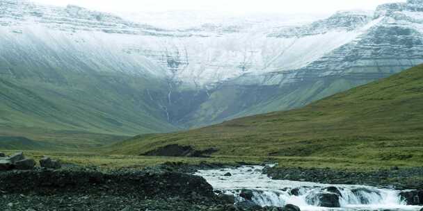 晴天下雪的河流在群山之间流动