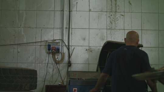 仓库里的男人检查他正在修理的轮胎