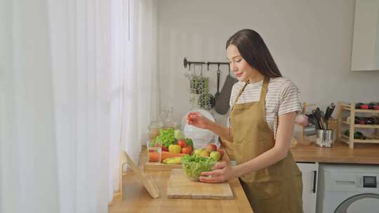 亚洲妇女在家厨房烹饪绿色健康沙拉的肖像。