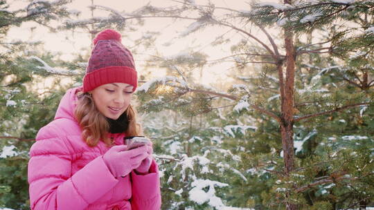 年轻女子在冬天的森林里使用手机
