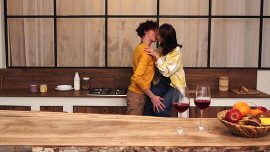 一对夫妇在现代厨房用一杯葡萄酒享受浪漫时