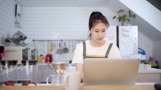 年轻女性烘培师在厨房使用笔记本电脑