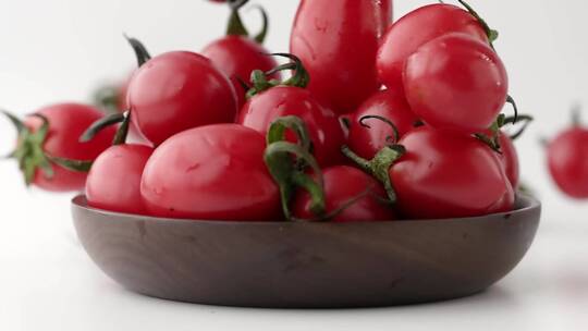 慢镜头特写拍摄落到碗中的新鲜有机小番茄