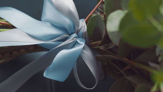 系在新鲜花束上的丝绸蓝丝带和蝴蝶结