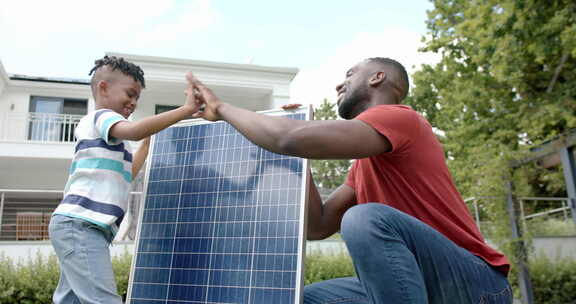 非裔美国父子在户外、家中的太阳能电池板旁