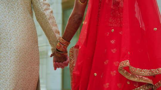 穿着传统印度服装牵手印度婚礼的夫妇一起散