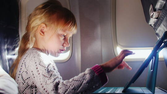 女孩在飞机上玩平板电脑