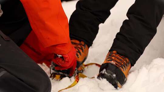 登山向导为攀登雪宝顶雪山的登山者穿戴冰爪