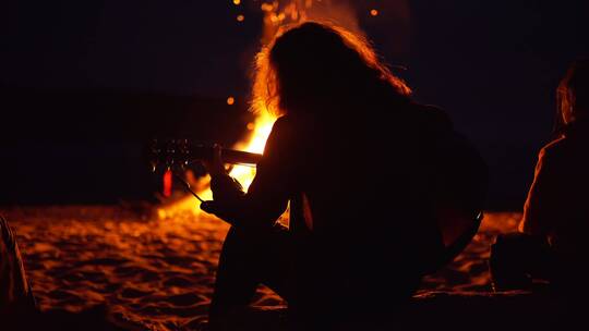 男人在海滩篝火旁弹吉他