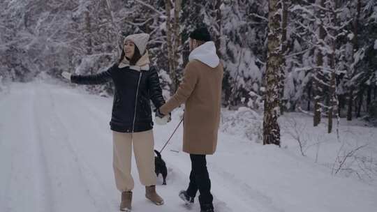 一对夫妇在雪地森林里遛狗