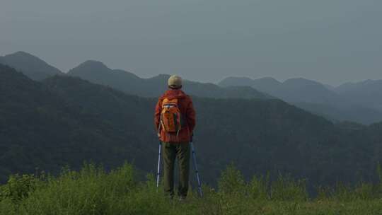 背包客持杖眺望连绵山脉