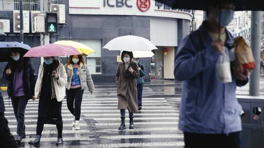 雨季下雨路边等待路人提伞过马路