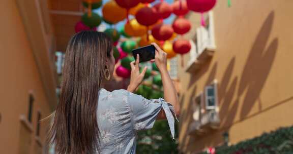 女人在户外用中国灯笼在手机上拍照