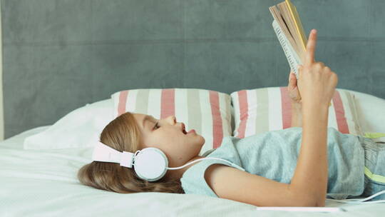 女孩听音乐并躺着看书