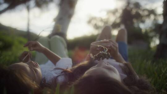两个女孩躺在草地上嗅花香