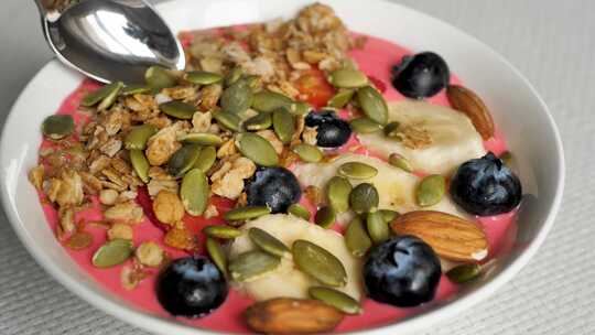 勺子取草莓和蓝莓的天然红色酸奶，加入香蕉