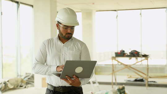 印度建筑工程师带着笔记本电脑和头盔在现场