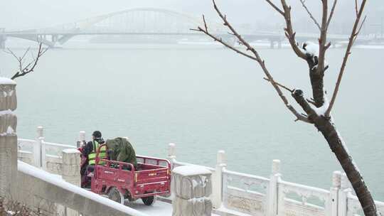 城市大雪中湖岸边的环卫工人