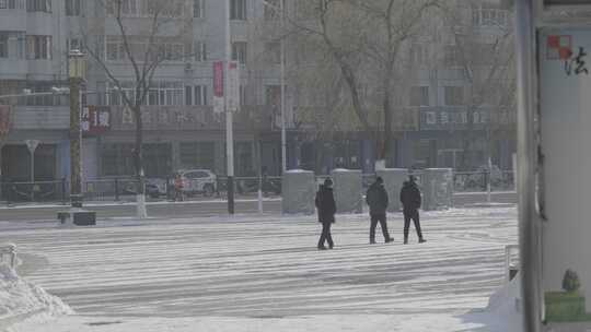 牡丹江市三人行走在被雪覆盖的城市道路上