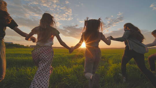 快乐的女孩牵着手穿过田野奔跑迎接夏日的阳光